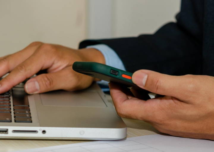 Segure um telemóvel e olhe para o computador e documentos de avaliação de satisfação de negócios na mesa
